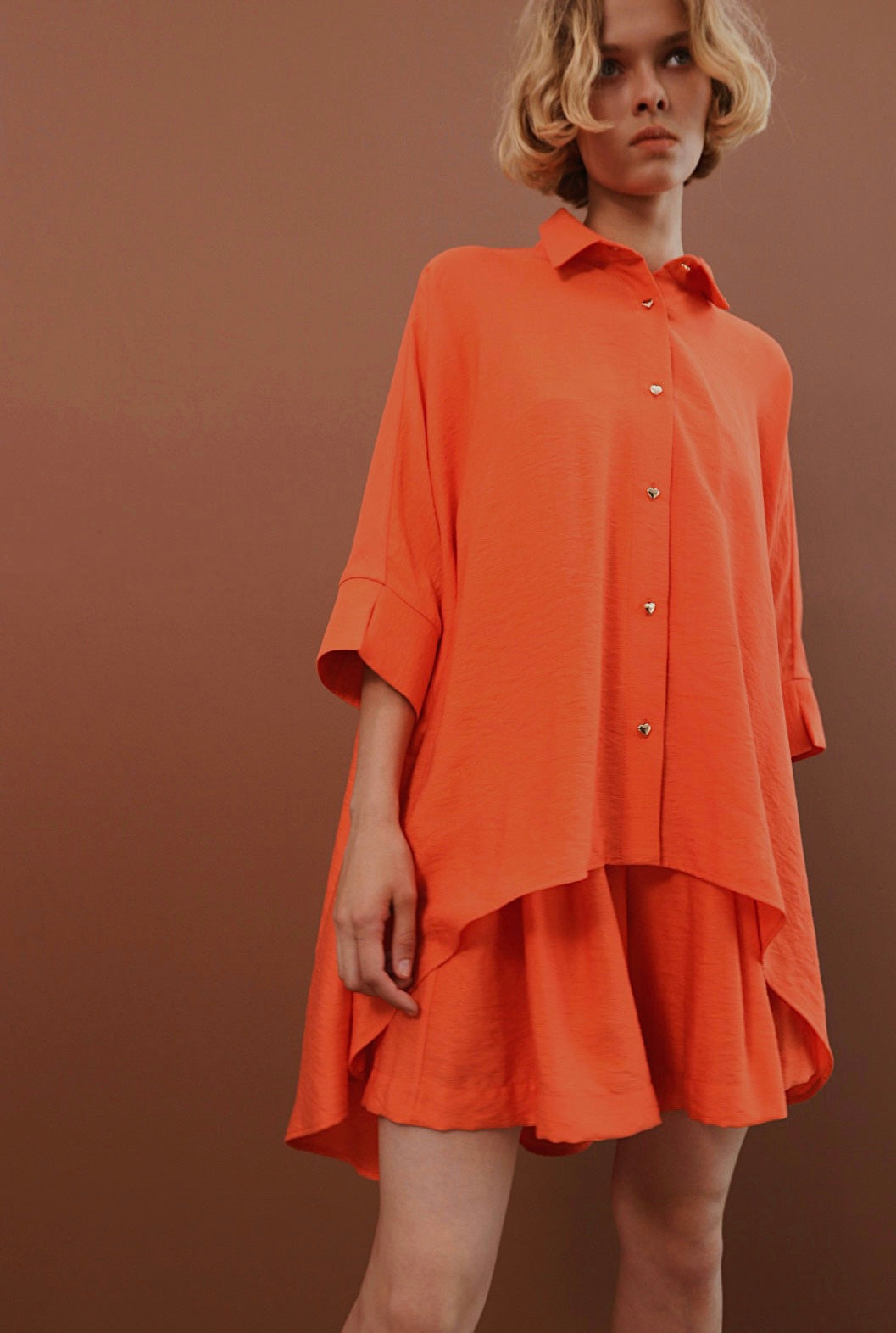 Traje naranja con shorts con botones en forma de corazón.