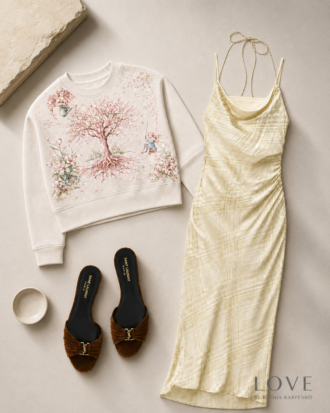 White sweatshirt with floral design, yellow dress, brown sandals, and a small dish on a light background.