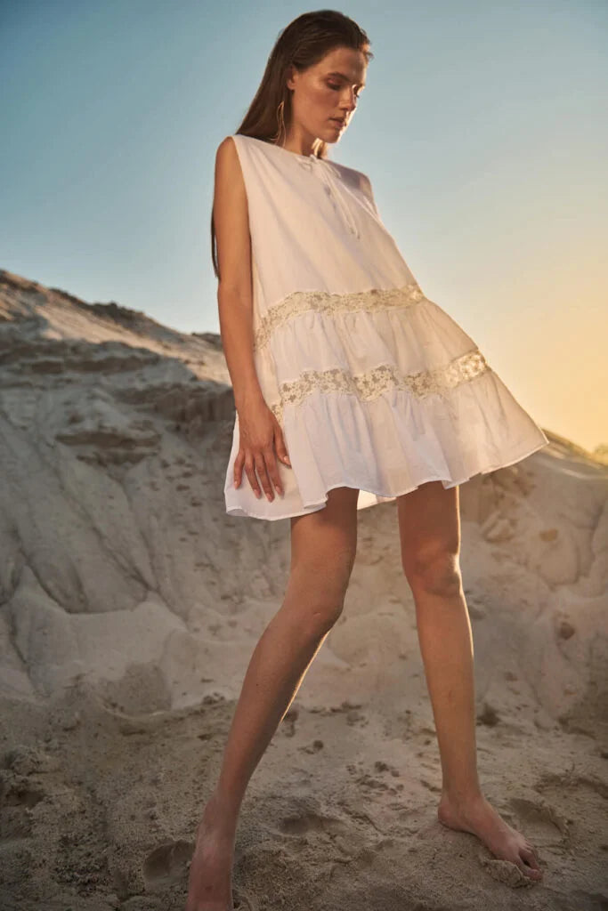 Vestido blanco mini corte en A, con inserciones decorativas de "margaritas" en la falda.